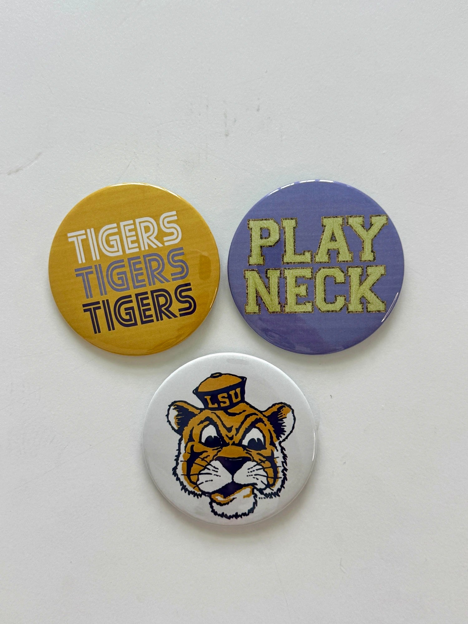 LSU game day pin-back button set featuring Tigers Tigers Tigers, Play Neck, and Tiger Mascot designs, from Chatsworth Boutique in Fairhope, Alabama.