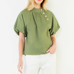 A model wearing the Olive Gold Button Blouse by THML, a woven button-up top in olive with gold button detail, from Chatsworth Boutique in Fairhope, Alabama.