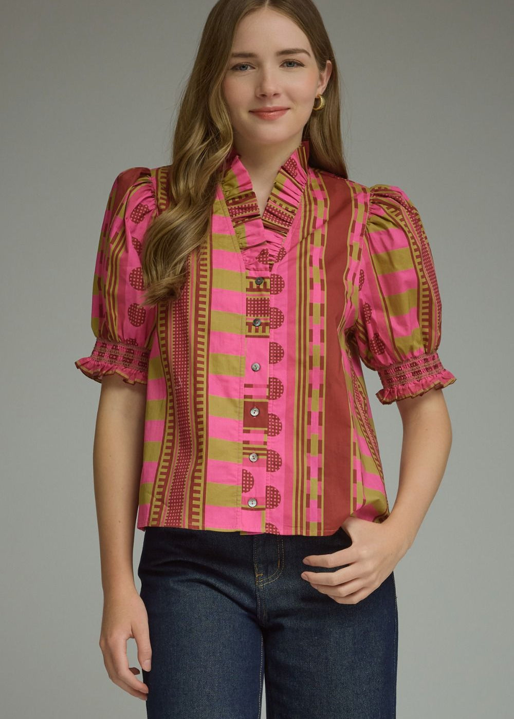 A model wearing the Stripes and Dots Blouse in pink and chartreuse by Entro, a mixed print top with a ruffle neckline and puff sleeves, from Chatsworth Boutique in Fairhope, Alabama.