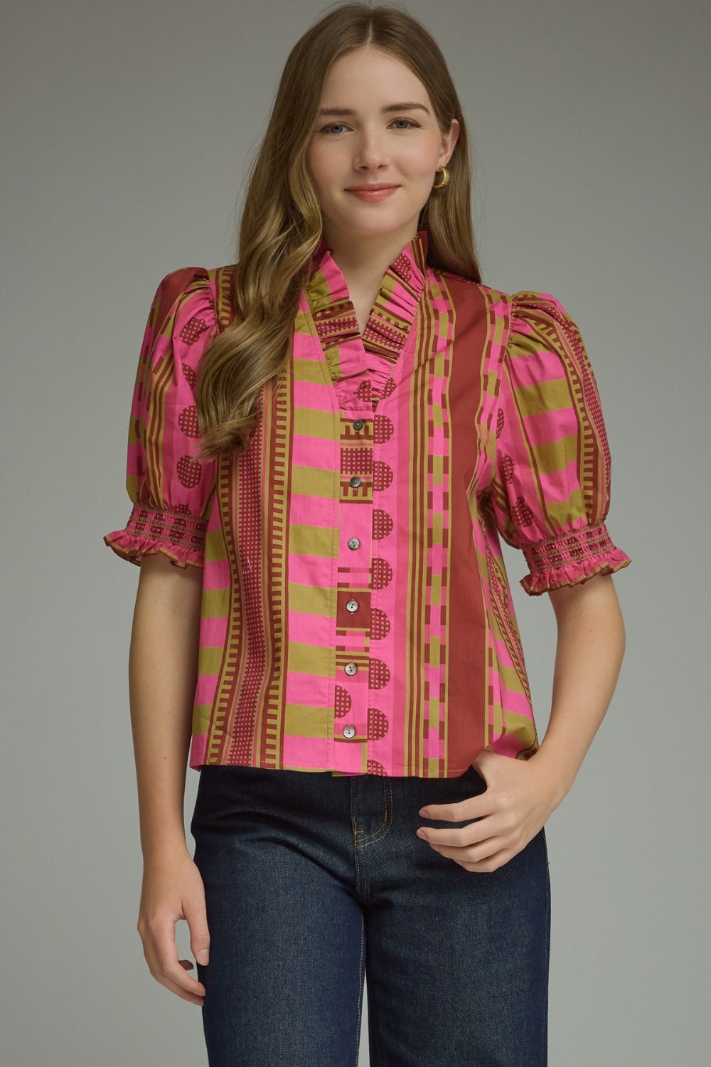 A model wearing the Stripes and Dots Blouse in pink and chartreuse by Entro, a mixed print top with a ruffle neckline and puff sleeves, from Chatsworth Boutique in Fairhope, Alabama.