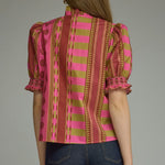 A model styling the Stripes and Dots Blouse in pink and chartreuse by Entro, from Chatsworth Boutique in Fairhope, Alabama.