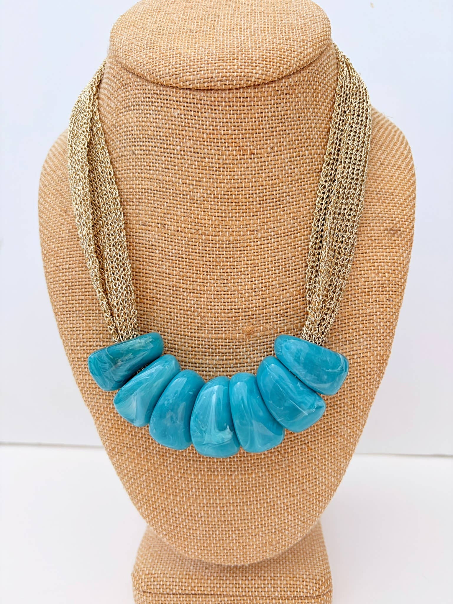 Necklace with turquoise beads on a tan bust